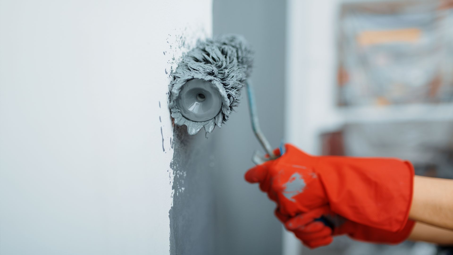 A person with red gloves is painting a wall