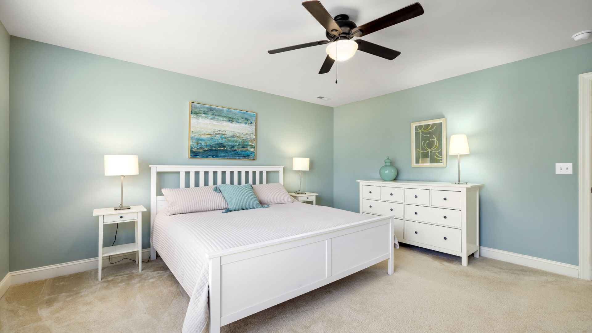 A bedroom with a bed, dresser, and ceiling fan